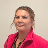 Hoivakodin yksikönpäällikkö Sannan kasvokuva, jossa punainen työasu päällä.
