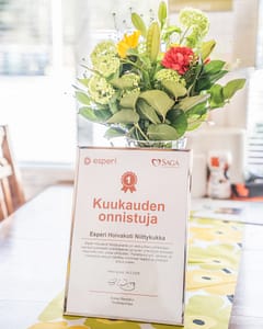 Kuukauden onnistuja diplomi hoivakodin pöydällä nojaamassa keväiseen kukkakimppuun.