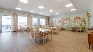 Tilava ruokailutila, jossa vaalea sisustus ja kukkakuvioinen tehosteseinä.