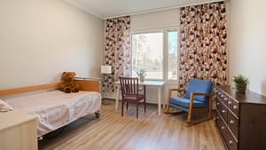 Asukashuone, sänky, kirjoituspöytä, tuoli ja ikkuna.