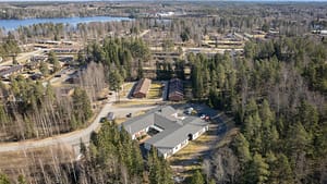 Hoivakoti ja ympäröivä asuinalue sekä järvimaisema ilmasta.