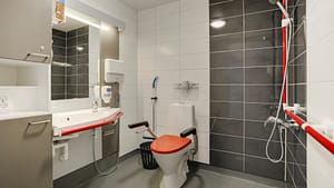 Esteetön kylpyhuone, suihku, tukikahvat ja korotettu wc-istuin.