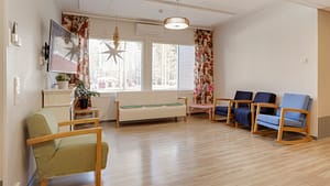 Viihtyisä oleskelutila, sohva ja useita nojatuoleja ikkunan äärellä.