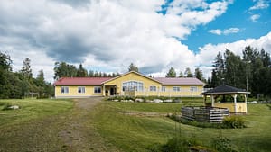 Esperi Koti Elmerin keltainen puurakennus vehreällä pihalla.