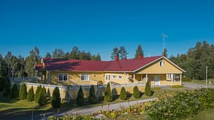 Esperi Koti Elmerin pihapiiri ja keltainen rakennus aurinkoisena päivänä.