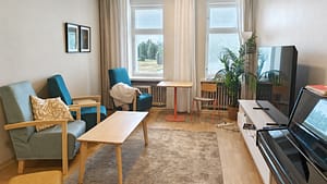 Kuurnan Kartanoiden viihtyisä olohuone nojatuoleineen ja pianoineen.