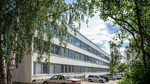 Esperi Koti Pitäjänmäen rakennuksen julkisivu, jossa on paljon ikkunoita ja rakennuksen pihassa parkkialue.
