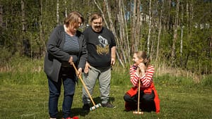 Esperi Koti Sypressin asukkaat pelaavat mailapeliä ohjaajan kanssa ulkona kesäisessä maisemassa.