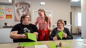 Esperi Koti Sypressin asukkaat askartelevat yhdessä ohjaajan kanssa yhteisessä olohuoneessa.