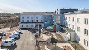 Hoivakodin piha-alue, jossa istuskelupaikkoja, ulkoilualue ja rakennuksen sisäänkäynti Kangasalla.