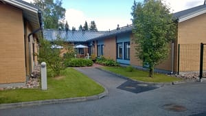 Rakennuksen julkisivua ja vehreää pihaa.