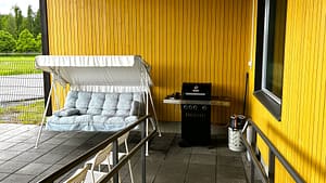 Katettu terassi, jossa on pehmustettuja istuimia ja grilli asukkaiden ulkoiluun ja yhdessäoloon.