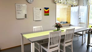 Valoisa ruokailutila, jossa on ruokapöytä, tuoleja ja ikkunasta tulevaa luonnonvaloa.