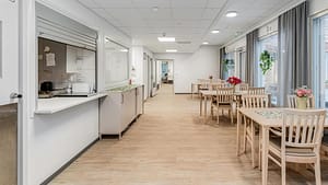 Valoisa käytävä, jonka varrella pöytiä ja tuoleja.