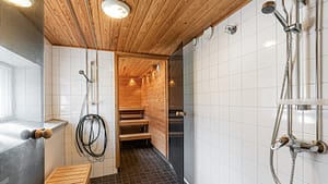 Suihkutila ja puupaneloitu sauna, lauteet ja lasiovi.
