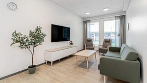 Oleskelutila, jossa seinätelevisio, penkki ja pöytä.