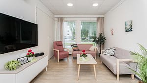 Valoisa oleskelutila, jossa sohvia, sohvapöytä ja viherkasveja.