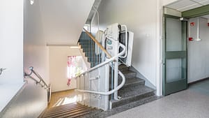 Sisäporras, jossa kaiteet ja porrashissi esteettömään liikkumiseen.
