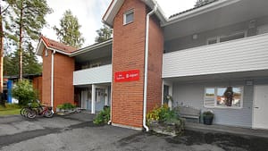 Punatiilinen rakennus ulkoa, seinässä opastekyltti.