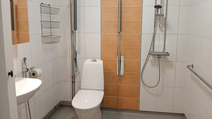 Esteetön kylpyhuone, jossa wc, suihku ja seinän tukikaiteet.
