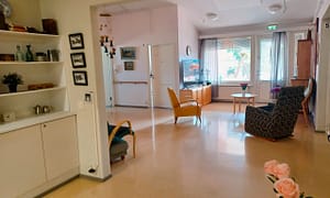 Hoivakodin valoisa oleskelutila, jossa hyllyjä, tuoleja ja muuta irtaimistoa.