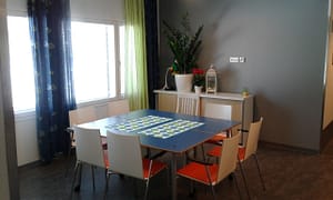 Hoivakodin ruokahuone, jossa näkyy pöytä ja tuoleja ikkunan edessä.