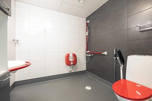 Esteetön kylpyhuone tukikaiteilla ja suihkutilalla.