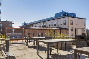 Kattoterassi ja oleskelualue useilla pöytäryhmillä kerrostalojen ympäröimänä.