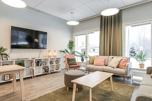 Valoisa ja kodikas yhteinen oleskelutila, jossa on sohvia ja televisio.