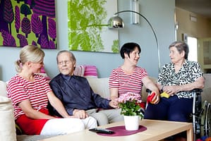Asukkaita ja hoitajia viettämässä yhteistä hetkeä hoivakodin oleskelutilassa
