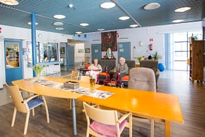 Oleskelutila, jossa huonekaluja ja ihmisiä istumassa.