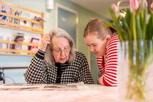 Kaksi henkilöä katsoo lehteä pöydällä.