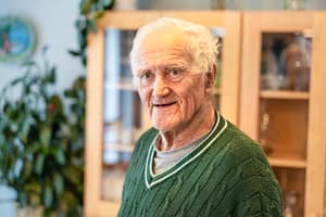 Kuva ihmisestä, taustalla kirjahylly ja huonekasveja.