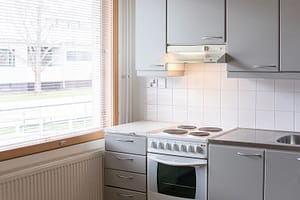 Tyhjä keittiö valoisan ikkunan edessä.