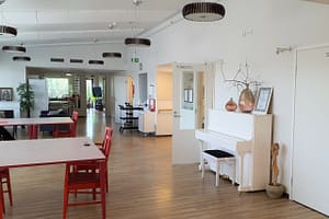 Kodin oleskelutilaa, näkyvillä piano, pöytiä ja tuoleja.