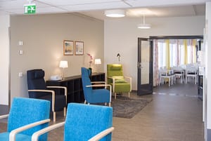 Hoivakodin avara ja valoisa olohuone, jossa näkyy tuoleja ja muita huonekaluja.