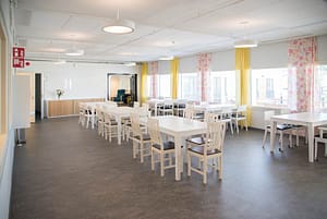 Avara ja valoisa huone hoivakodin sisältä, jossa on huonekaluja.