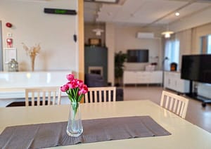 Yhteistilan pöytä, jossa kukkakimppu maljakossa.