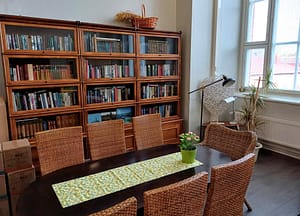 Huone, jossa pöytä ja tuoleja, sekä iso kirjahylly.