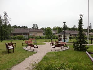 Hoivakodin vehreä piha-alue, jossa terassikalusteita.