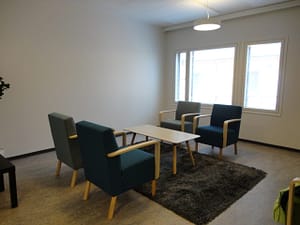 Hoivakodin olohuone, jossa näkyy tuoleja ja pöytä ikkunan edustalla.