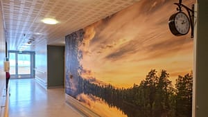 Hoivakodin käytävä, jossa suuri järvimaisemaa esittävä seinäkuva.