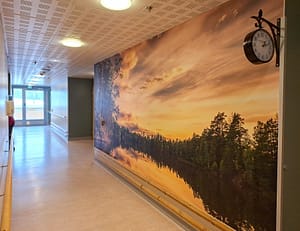 Hoivakodin käytävä, jossa suuri järvimaisemaa esittävä seinäkuva.