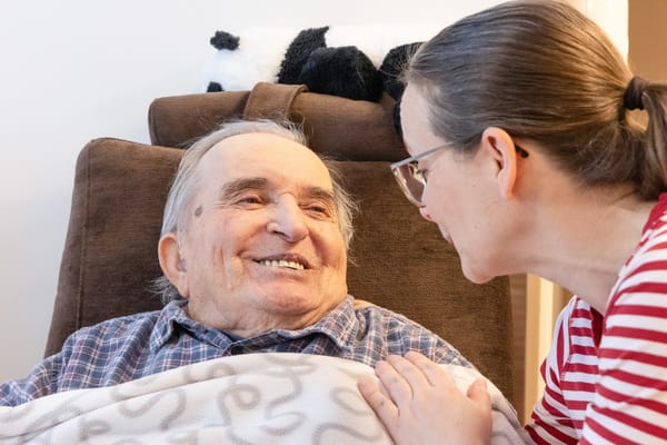 Asukas ja hoitaja keskustelevat hyväntuulisesti.