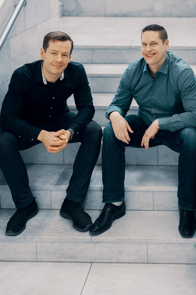 Two men sitting side by side in a staircase.