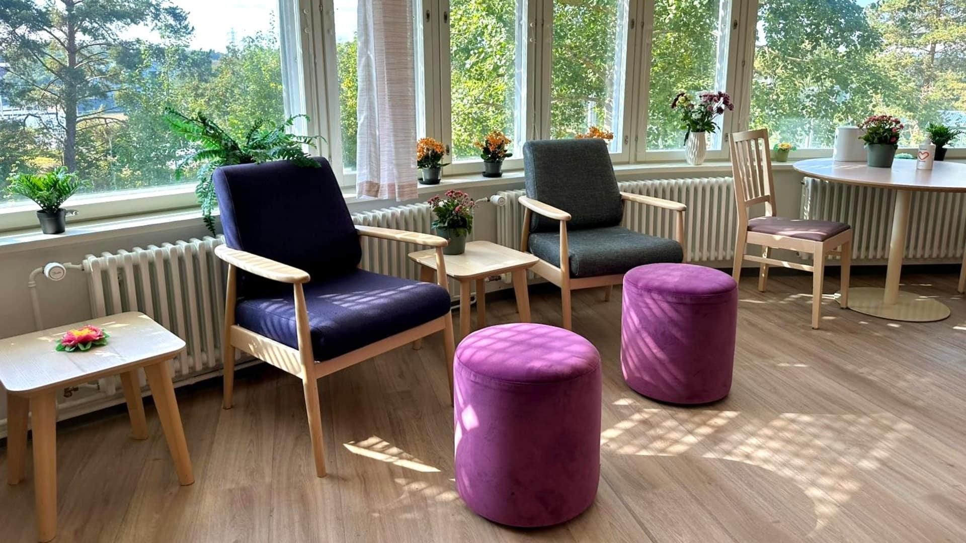 Valoisa oleskelutila, jossa on kaksi nojatuolia ja jalkarahit