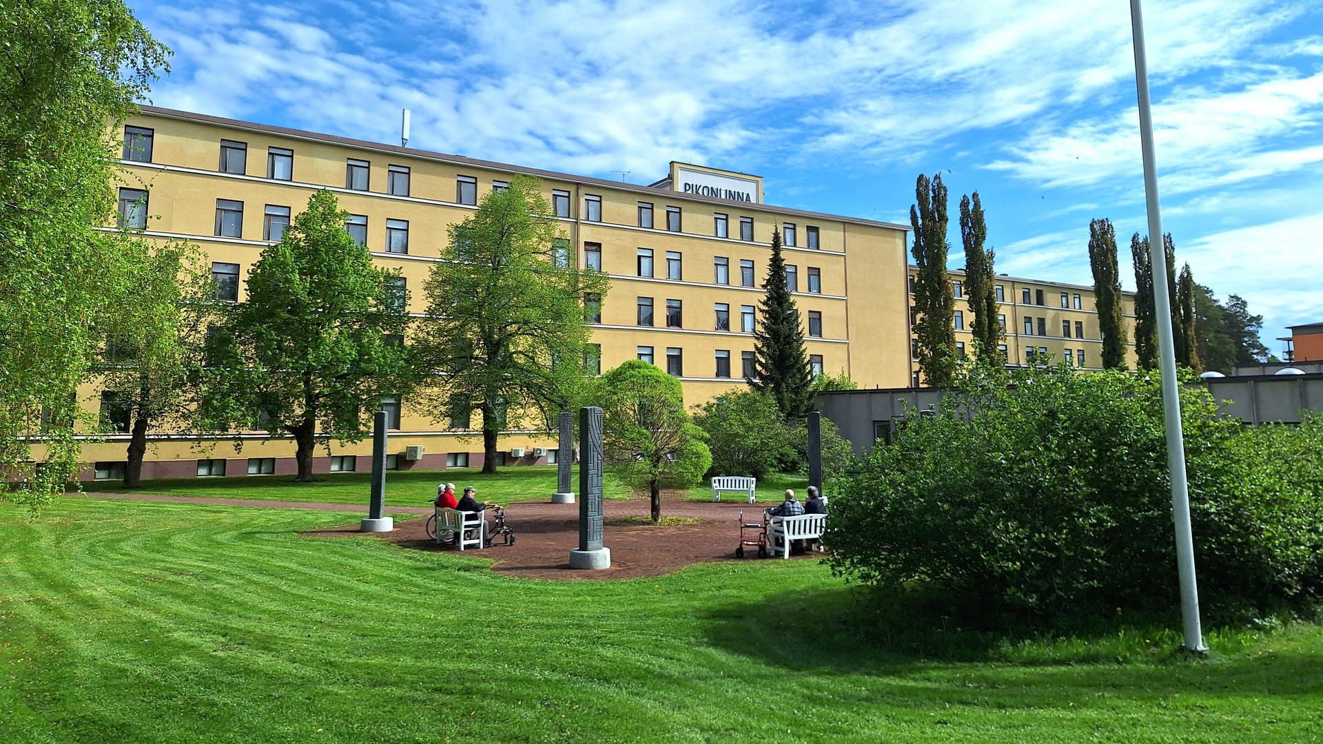 Hoivakodin rakennus ja vehreä piha-alue kesäpäivänä