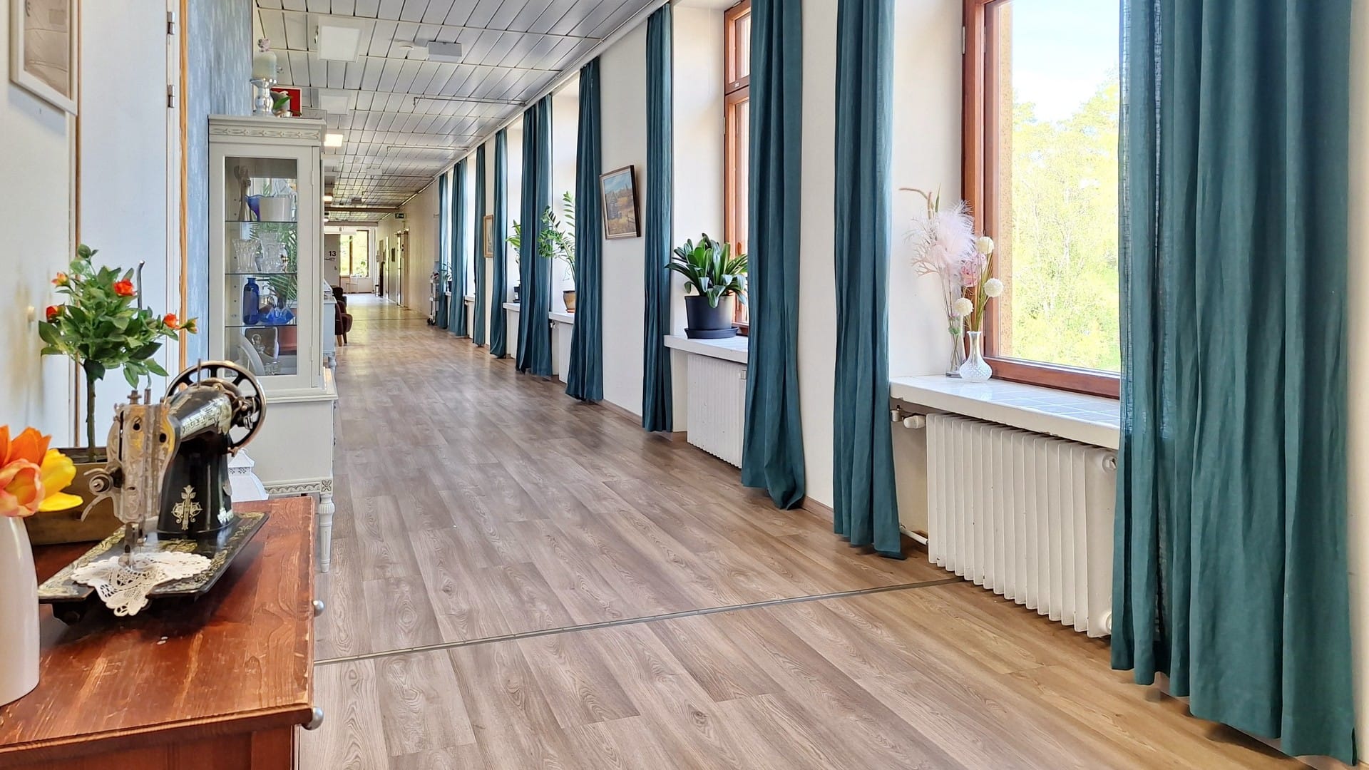 Valoisa käytävä sinisine verhoineen ja suurine ikkunoineen