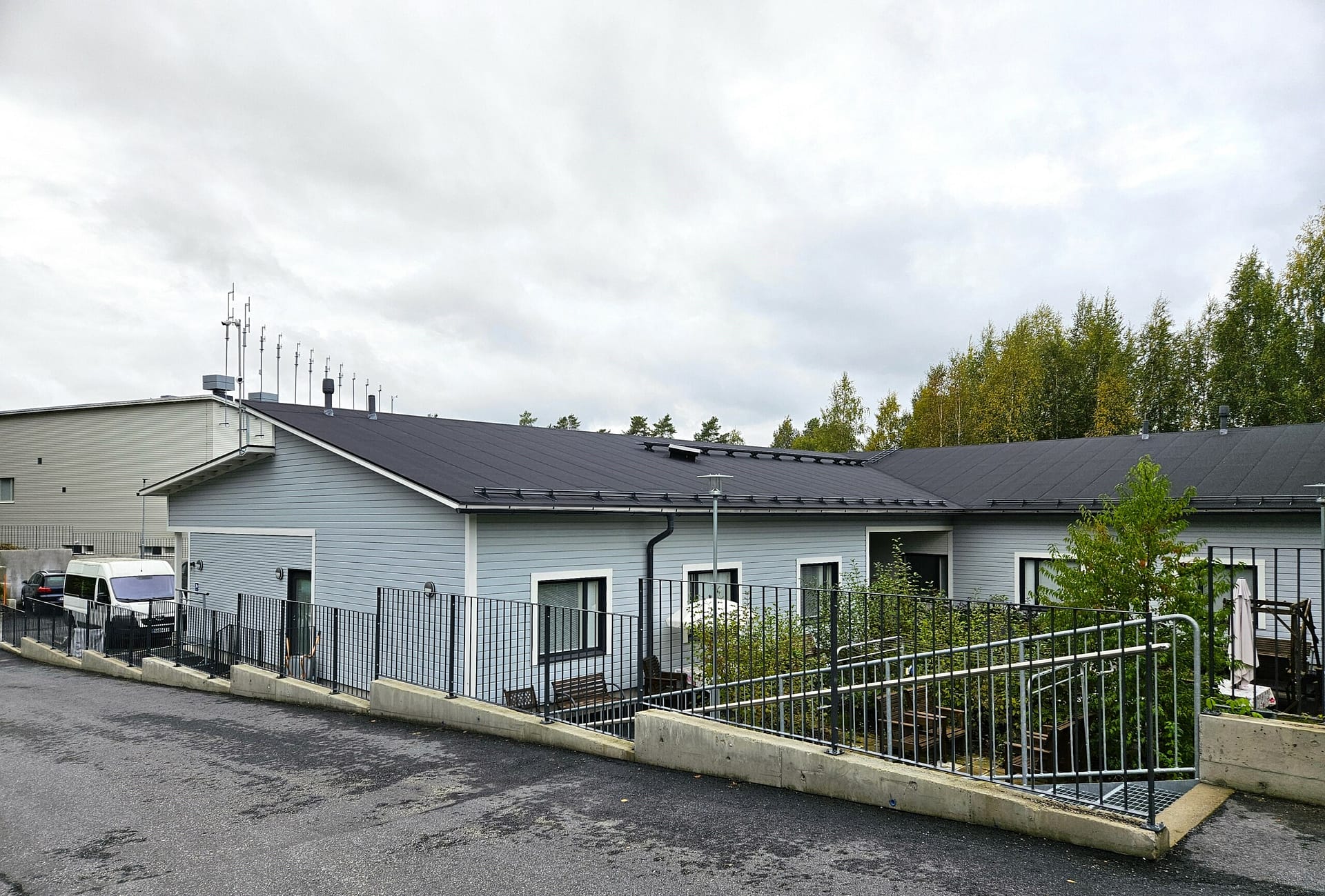 Palvelukodin rakennus ja aidattu piha-alue ulkoa kuvattuna.