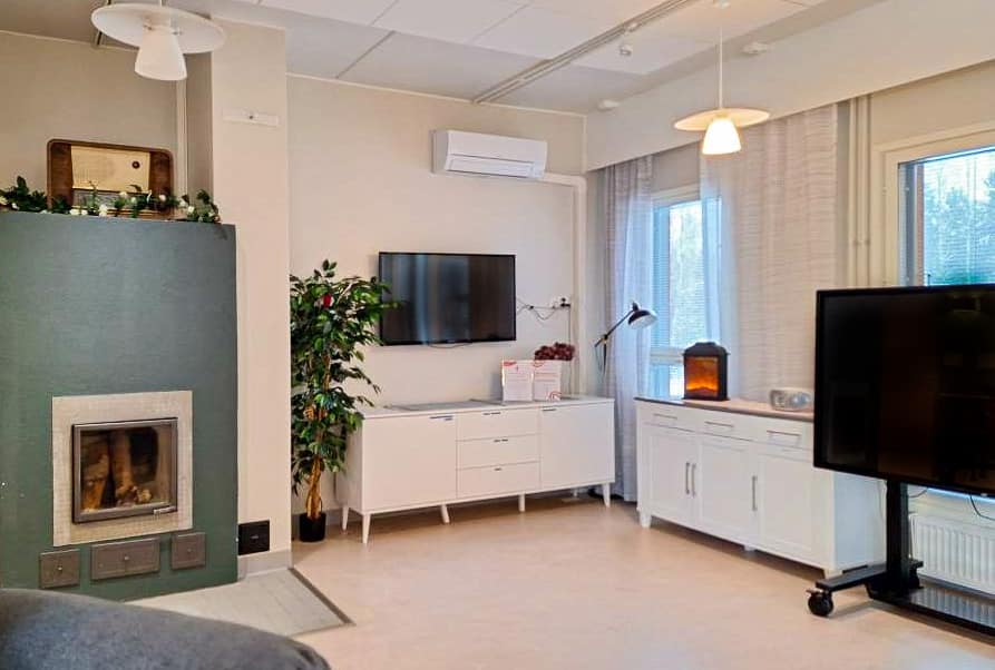 Hoivakodin viihtyisä yhteinen oleskelutila ja televisio.